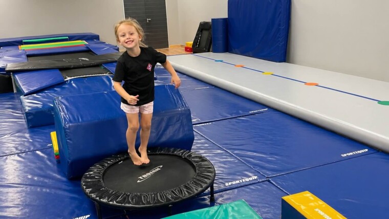 Young girl enjoying kids gymnastics classes while jumping on a mini trampoline